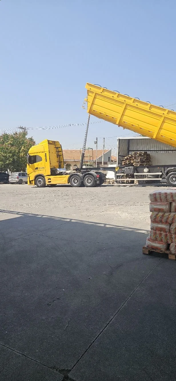 Caminhão amarelo descarregando na fábrica